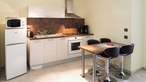 A compact kitchen with a microwave, oven, and coffee maker. There is a dining table with four chairs. - Entre Plages & Espagne : Ferme de Charme, Pistes cyclables & Baignade Bio (Orx)