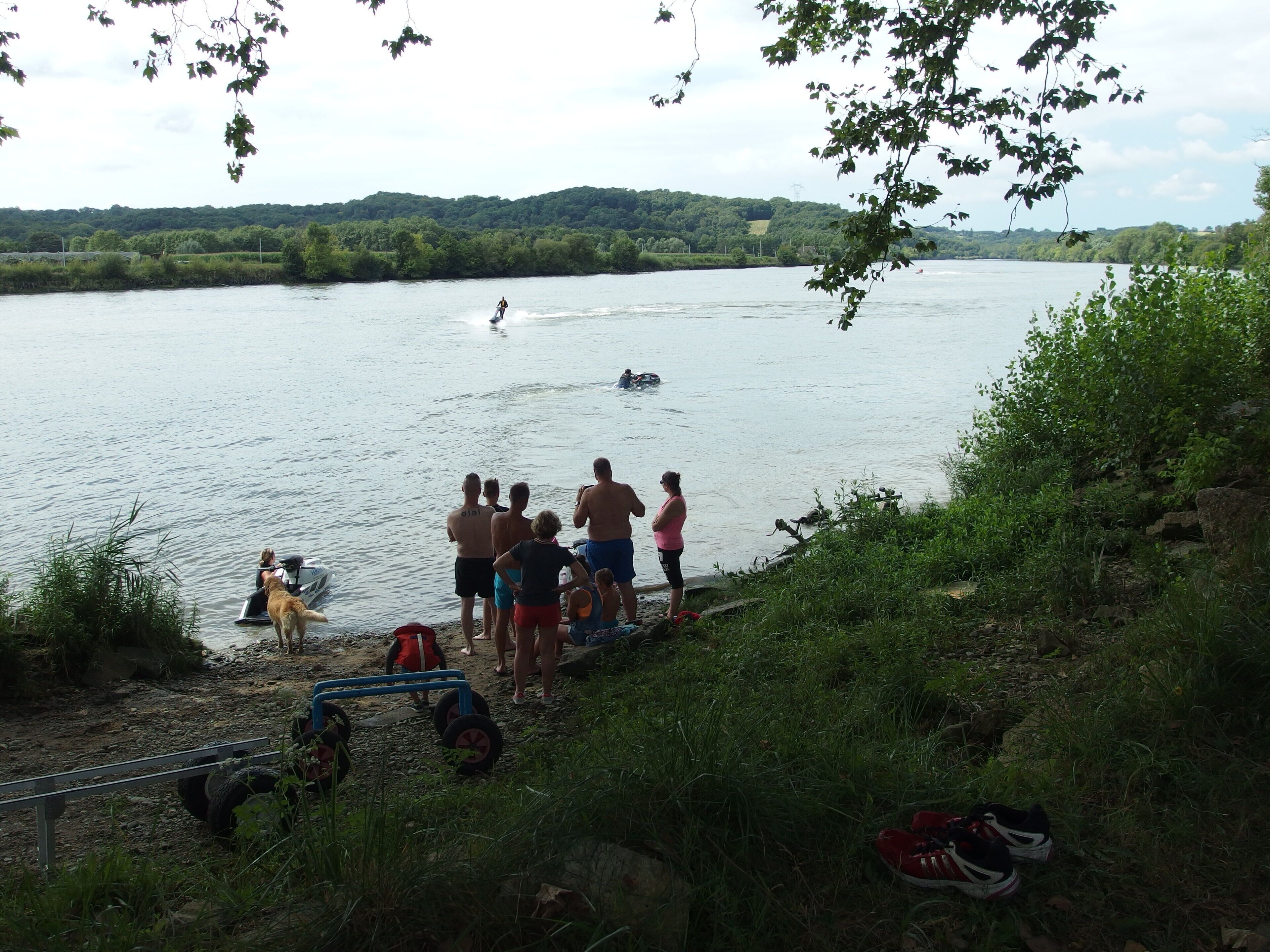 Un groupe de personnes observe un pratiquant de wakeboard sur une rivière.