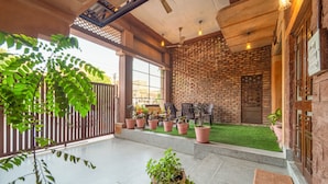 A spacious indoor area with a brick wall, potted plants, and a small artificial grass section. - The Munshi Mansion (Jodhpur)