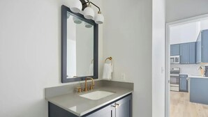 Un baño moderno con un espejo grande, un lavabo y un inodoro.