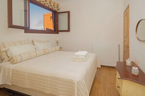 A neatly made bed with a striped pillow set, a bedside lamp, and a stack of folded towels.