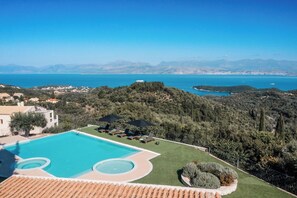 A pool with a view of the sea and mountains.