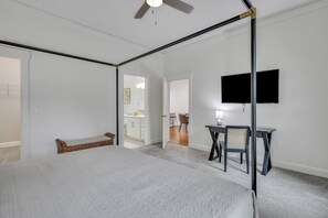 Un dormitorio con una cama grande, un escritorio, una silla y un televisor en la pared.