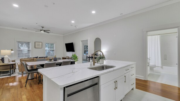 A modern kitchen with a white marble countertop, stainless steel sink, and built-in dishwasher. - Modern 2BDR ADA in Walkable Historic District | The Juliette #102 by AvantStay (Savannah)