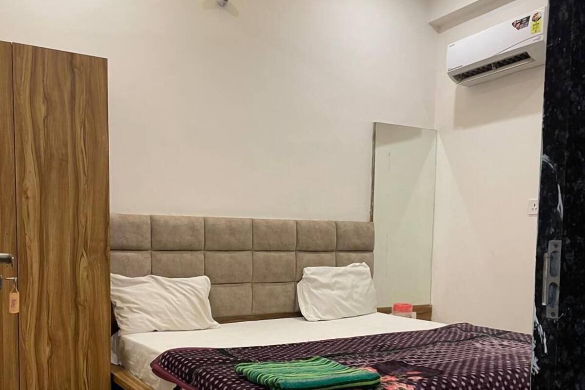 A bedroom with a wooden bed, a mirror, and an air conditioning unit.