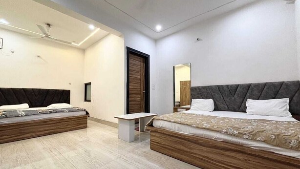 A modern bedroom with two beds, a small table, and a mirror. - Devi Heritage Vrindavan (Vrindavan)