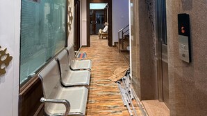 Una hall d'albergo con reception, area salotto e ascensore.