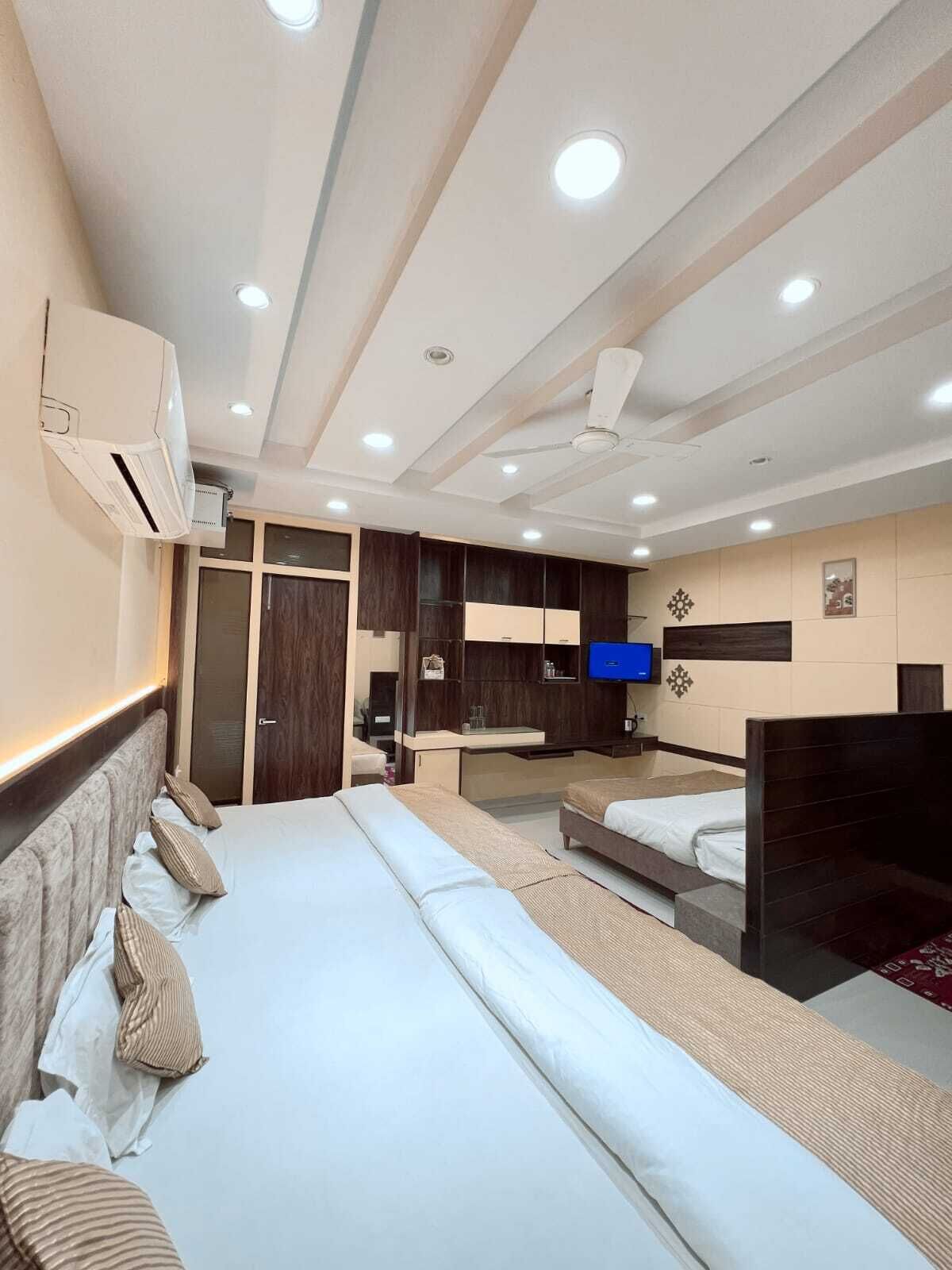 A hotel room with a large bed, a desk, a TV, and a wardrobe.