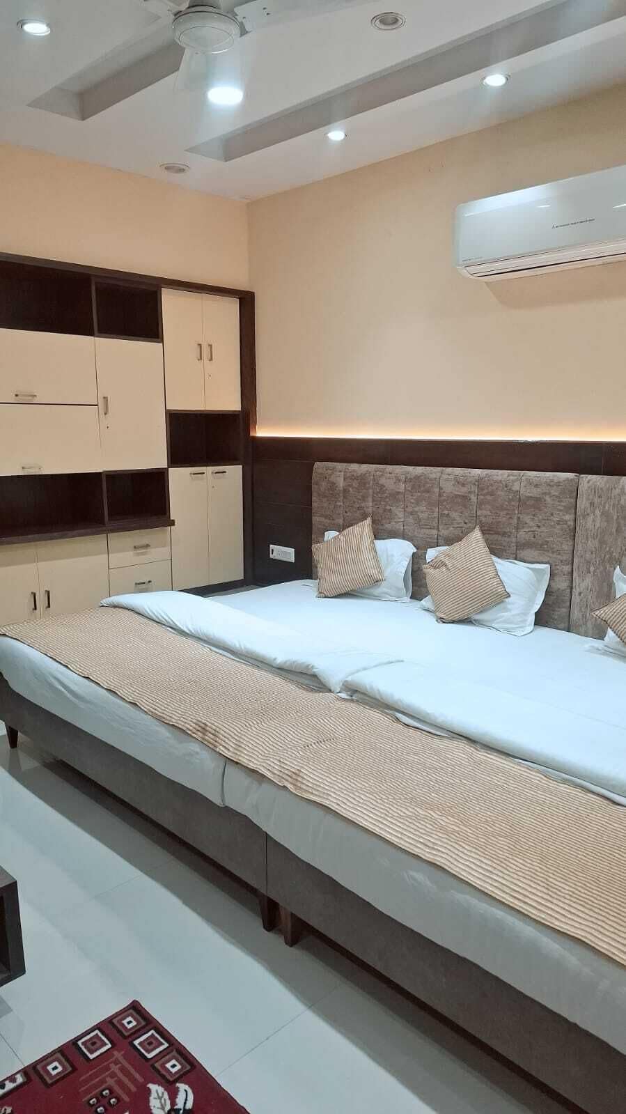 A bedroom with a large bed, built-in wardrobe, and an air conditioning unit.