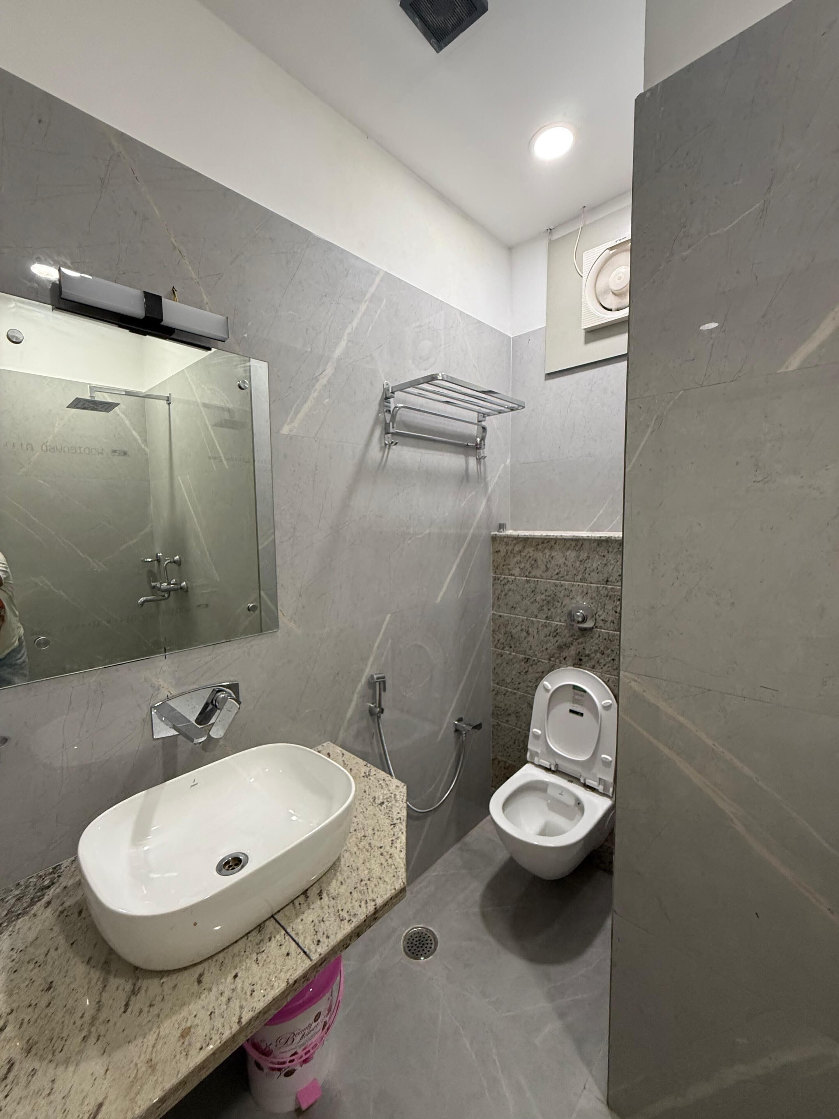 Een moderne badkamer met een glazen douchecabine, een wit wastafelmeubel en een toilet.