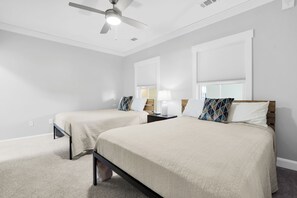Ein Schlafzimmer mit zwei Betten, einem Deckenventilator und einem Fenster mit Jalousien.