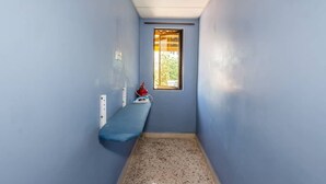 A narrow hallway with blue walls, a small bench, a window, and a fire extinguisher. - OYO 91258 Qish Hotel Banda Kaba (Malacca City)