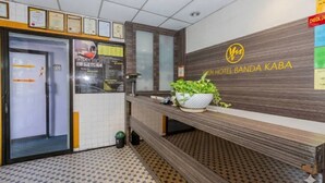 A reception area with a check-in counter, framed certificates on the wall, and a potted plant. - OYO 91258 Qish Hotel Banda Kaba (Malacca City)