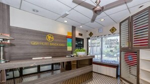 A reception area with a wooden reception desk, a ceiling fan, and a patterned floor. - OYO 91258 Qish Hotel Banda Kaba (Malacca City)