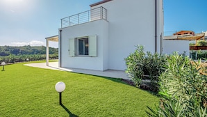 Una casa moderna de dos pisos con techo plano, un balcón y un césped cuidado.