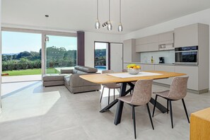 Eine moderne Küche mit Essbereich, großen Fenstern und Blick auf einen Pool.