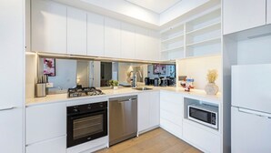 Eine moderne Küche mit weißen Schränken, Edelstahlgeräten und einer eingebauten Mikrowelle.