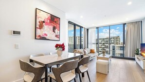 Ein modernes Wohnzimmer mit Essbereich, großen Fenstern und Blick auf die Stadt.