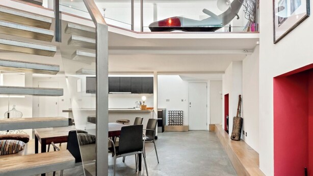 A modern interior with a staircase leading to a loft area, a dining area with a table and chairs, and a kitchen with cabinets and a countertop. - Architect design maisonette in top location in Holland Park (London)