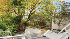 A glass-enclosed outdoor area with a metal chair, potted plants, and a wooden fence. - Architect design maisonette in top location in Holland Park (London)