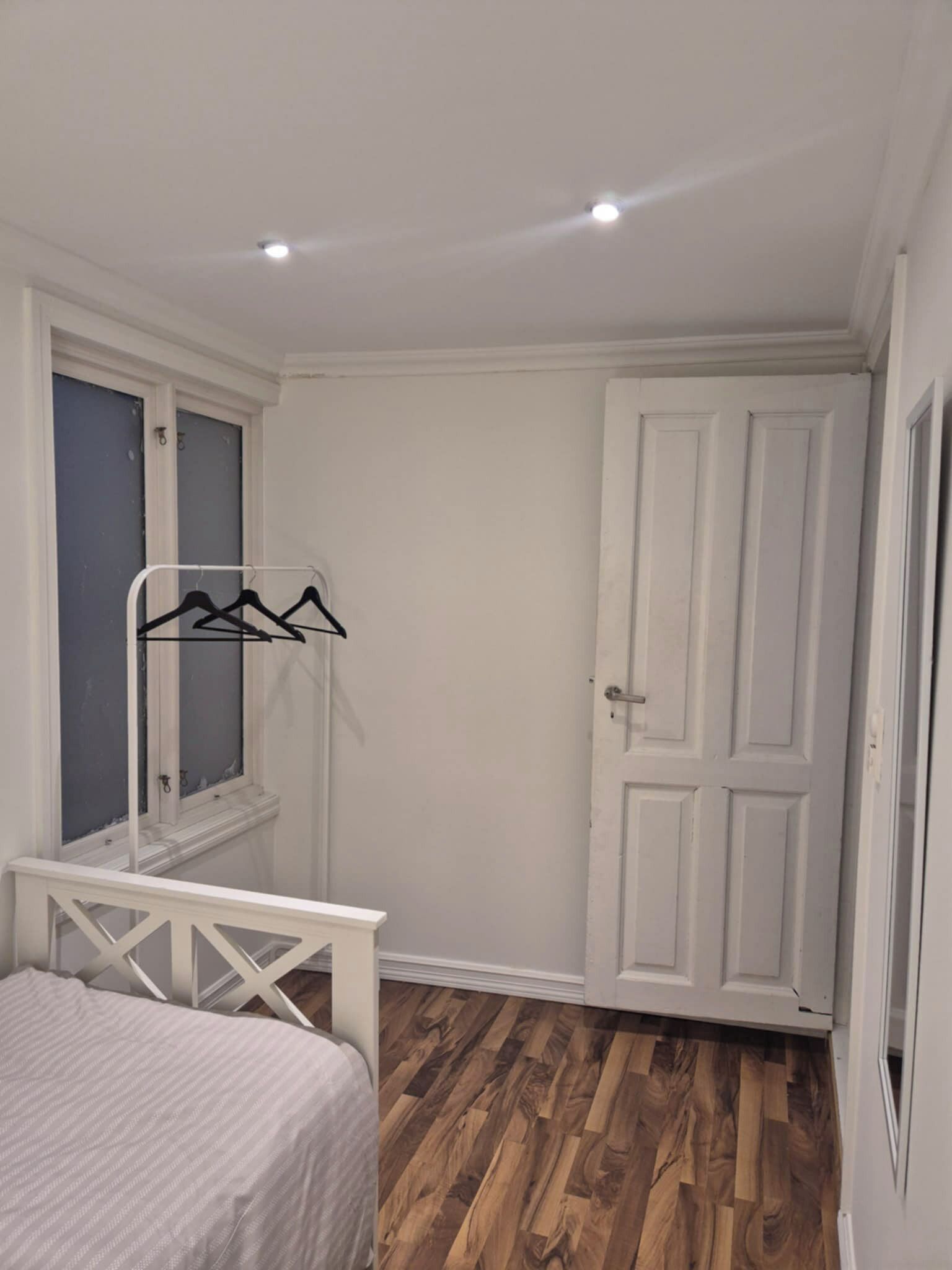 Een slaapkamer met een bed, een kledingkast, een spiegel en een deur.