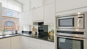 Eine moderne Küche mit weißen Schränken, einer Edelstahl-Mikrowelle und einem Backofen.