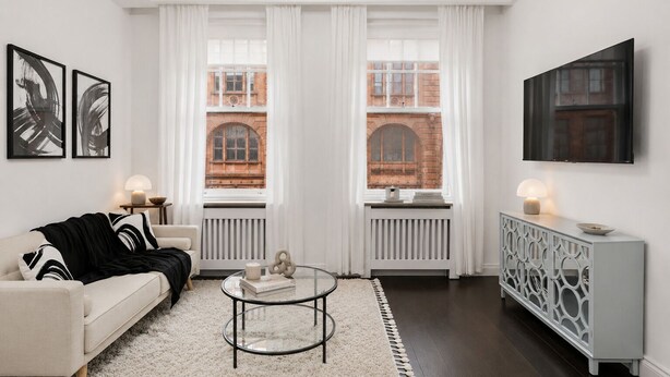 Ein modernes Wohnzimmer mit einer Couch, einem Couchtisch und einem an der Wand montierten Fernseher.
