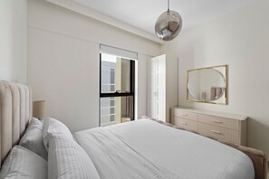 A modern bedroom with a large bed, a wardrobe, a radiator, and a mirror. - 1BR Balcony & Luxury Amenities (Dubai)