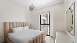 Ein Schlafzimmer mit einem großen Bett, einem Nachttisch, einem Spiegel und Blick auf den Balkon.