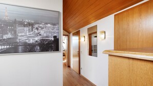 A corridor with a wooden ceiling, a framed cityscape photograph, and a wooden counter. - Apartment "Omas volle Hütte" with Mountain View, Private Terrace and Wi-Fi (Mühltal)