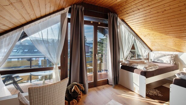 A bedroom with a loft bed, a window with curtains, a view of the outside, and a small table. - Apartment "Omas volle Hütte" with Mountain View, Private Terrace and Wi-Fi (Mühltal)
