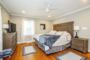 A bedroom with a bed, nightstands, a dresser, a ceiling fan, and a window with curtains. - Country Comfort Hideaway (Julian)
