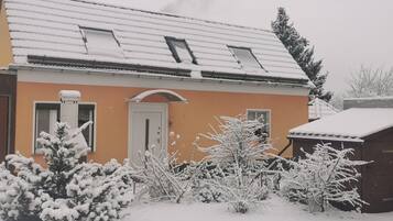 Ein Haus mit schneebedecktem Dach, einer sichtbaren Tür und Fenstern.