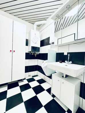Een moderne badkamer met een zwart-wit schaakbordvloer, witte kastjes en een witte wasbak.