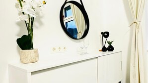 A white cabinet with a mirror, a potted orchid, and a small black object on top. - Luxury 7 Bedroom Apartment Sleeps 16 (Vienna)