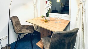 A small dining area with a wooden table, two chairs, a floor lamp, and a window with curtains. - Luxury 7 Bedroom Apartment Sleeps 16 (Vienna)