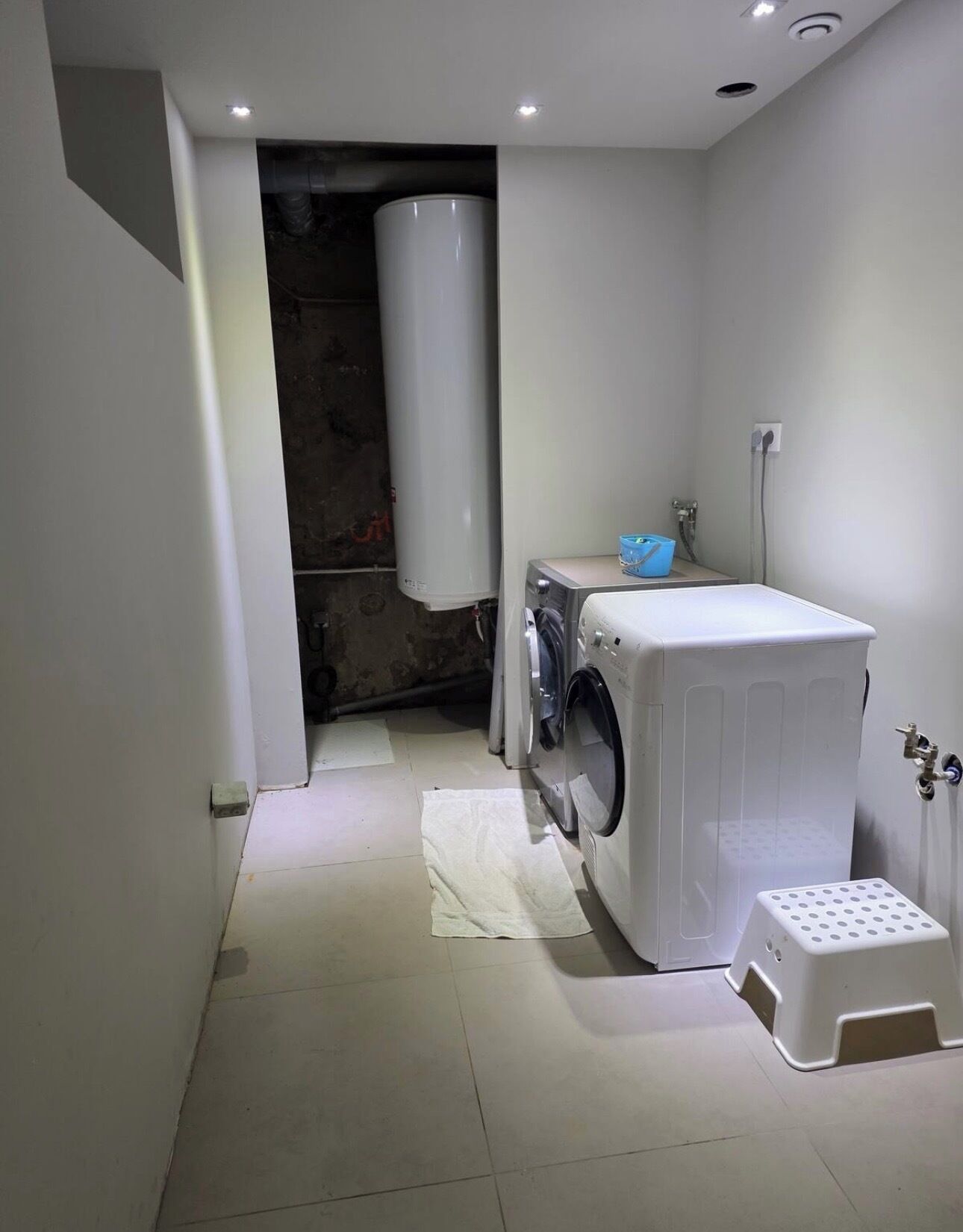 Ein kleiner Hauswirtschaftsraum mit Waschmaschine, Trockner und Warmwasserbereiter.