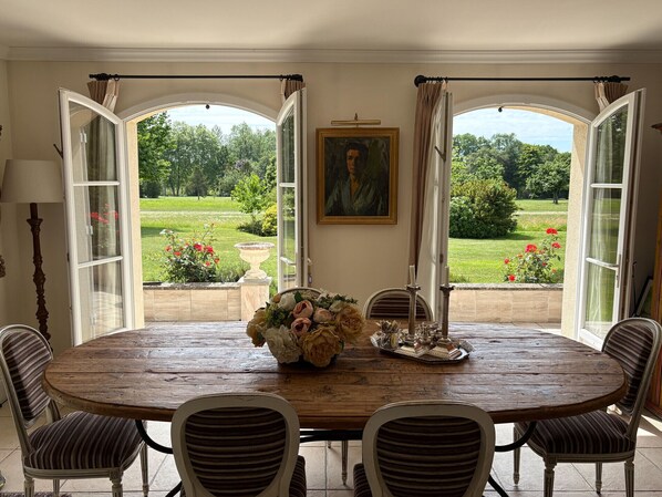 A dining room with a wooden table, striped chairs, a vase of flowers, and a painting on the wall.
