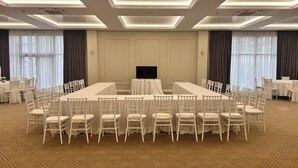 A conference room with a long table surrounded by chairs, a television, and large windows with curtains. - River Park Dragasani (Drăgășani)