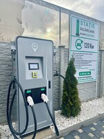Una estación de carga con un cartel que indica una capacidad de 120 kW y una tarifa de 2,20 lei por kWh.
