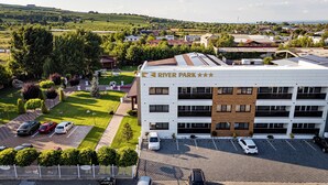 A hotel named River Park with a modern design, featuring a parking area and a landscaped garden. - River Park Dragasani (Drăgășani)
