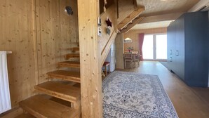 Ein Holzinnenraum mit einer Treppe, einem gemusterten Teppich und Blick nach draußen.