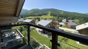 Eine Holzhütte mit einem Balkon, der Blick auf ein Dorf und Berge bietet.