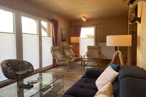 A wooden interior with a sofa, two armchairs, a glass coffee table, and a lamp. - Chalet with infrared sauna (Hohentauern)