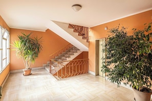 Ein geräumiger Innenraum mit Treppe, Blumentöpfen und einer Tür.