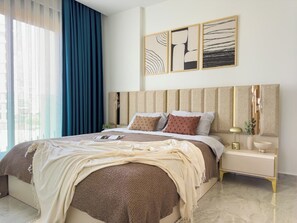 Ein modernes Schlafzimmer mit einem großen Bett, einem Nachttisch mit Lampe und abstrakter Wandkunst.