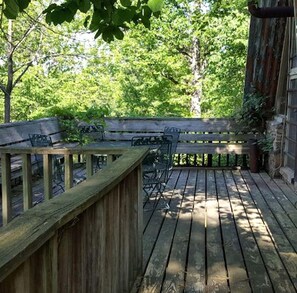 Eine Holzterrasse mit einer Bank und Stühlen, umgeben von Bäumen.