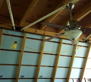 Ein Zimmer mit freiliegenden Holzbalken, einem Deckenventilator und einer Hängelampe.