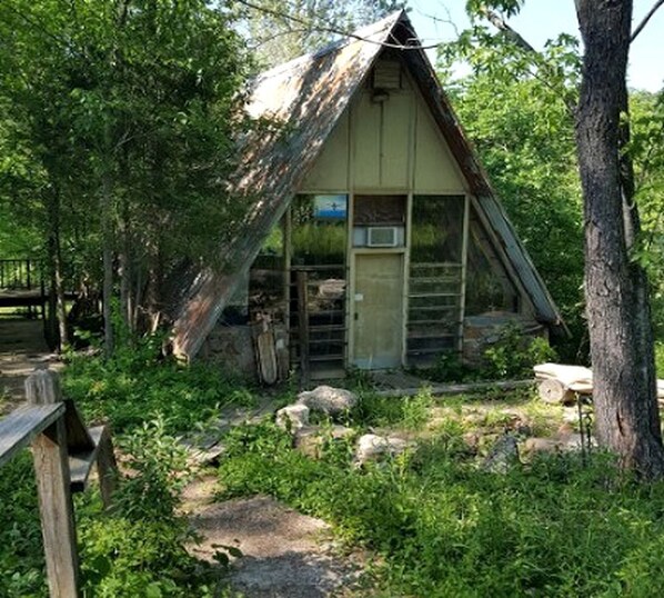 Eine rustikale Holzhütte mit geneigtem Dach, einer kleinen Veranda und einer Tür.