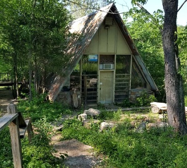 Une cabane rustique avec un toit en pente, un petit porche et une porte.